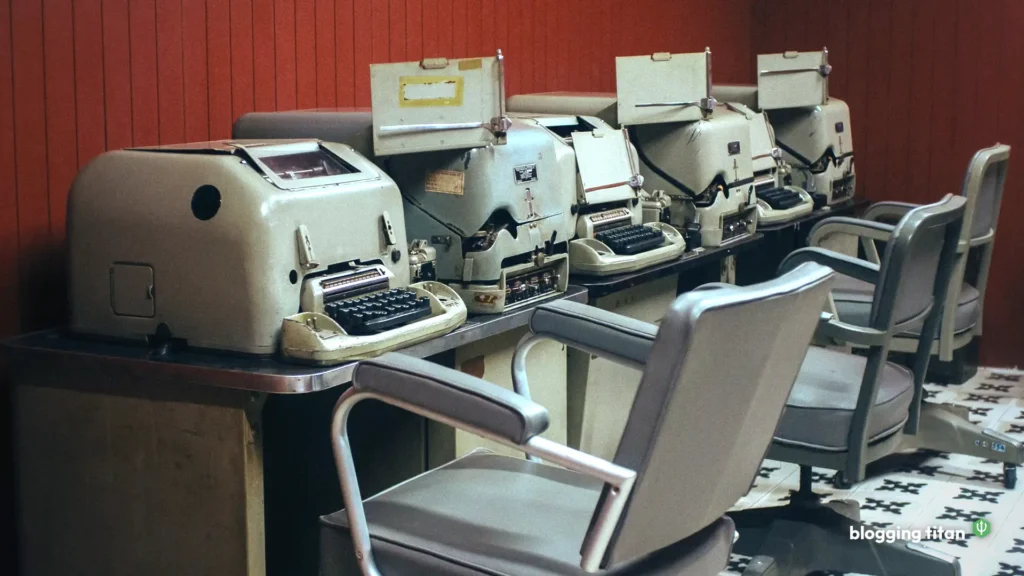 A row of vintage typewriters at identical desks with empty office chairs, the featured image for our same-brief AI writing test - Blogging Titan